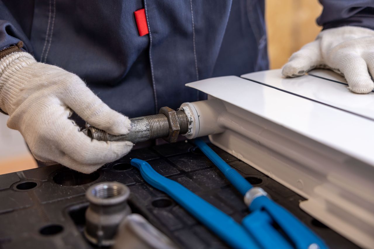 Services Close-up of a plumber installing a radiator pipe using specialized tools.
