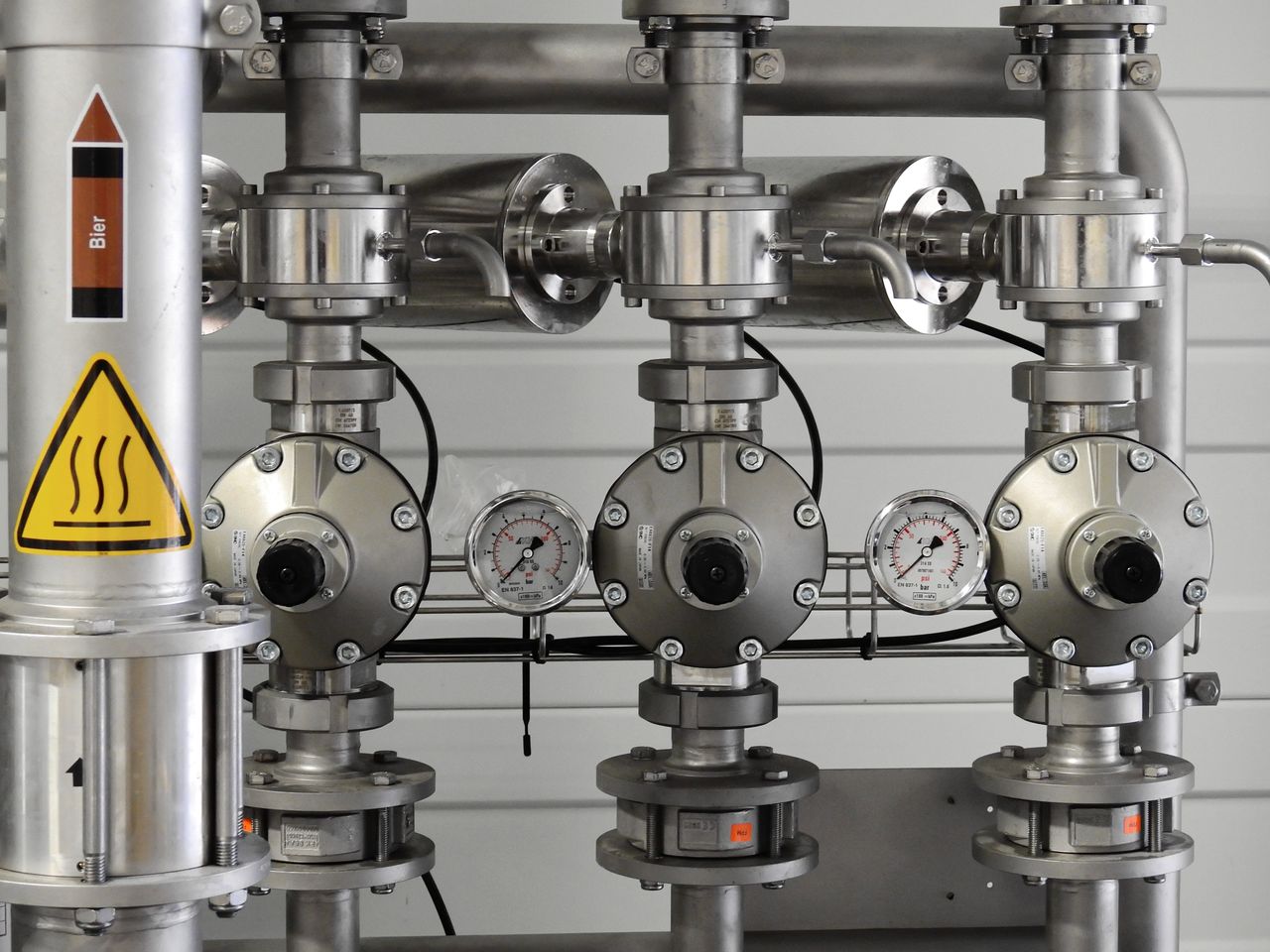 Services Close-up of stainless steel pipes with pressure gauges in an industrial setting.